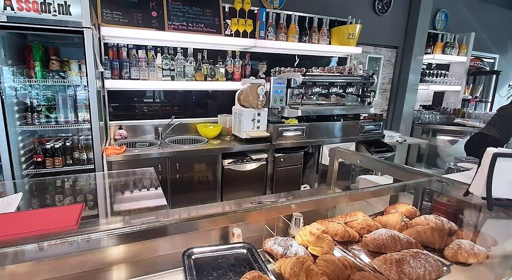 Il bancone del bar con la macchina del caffè e i cornetti in vetrina