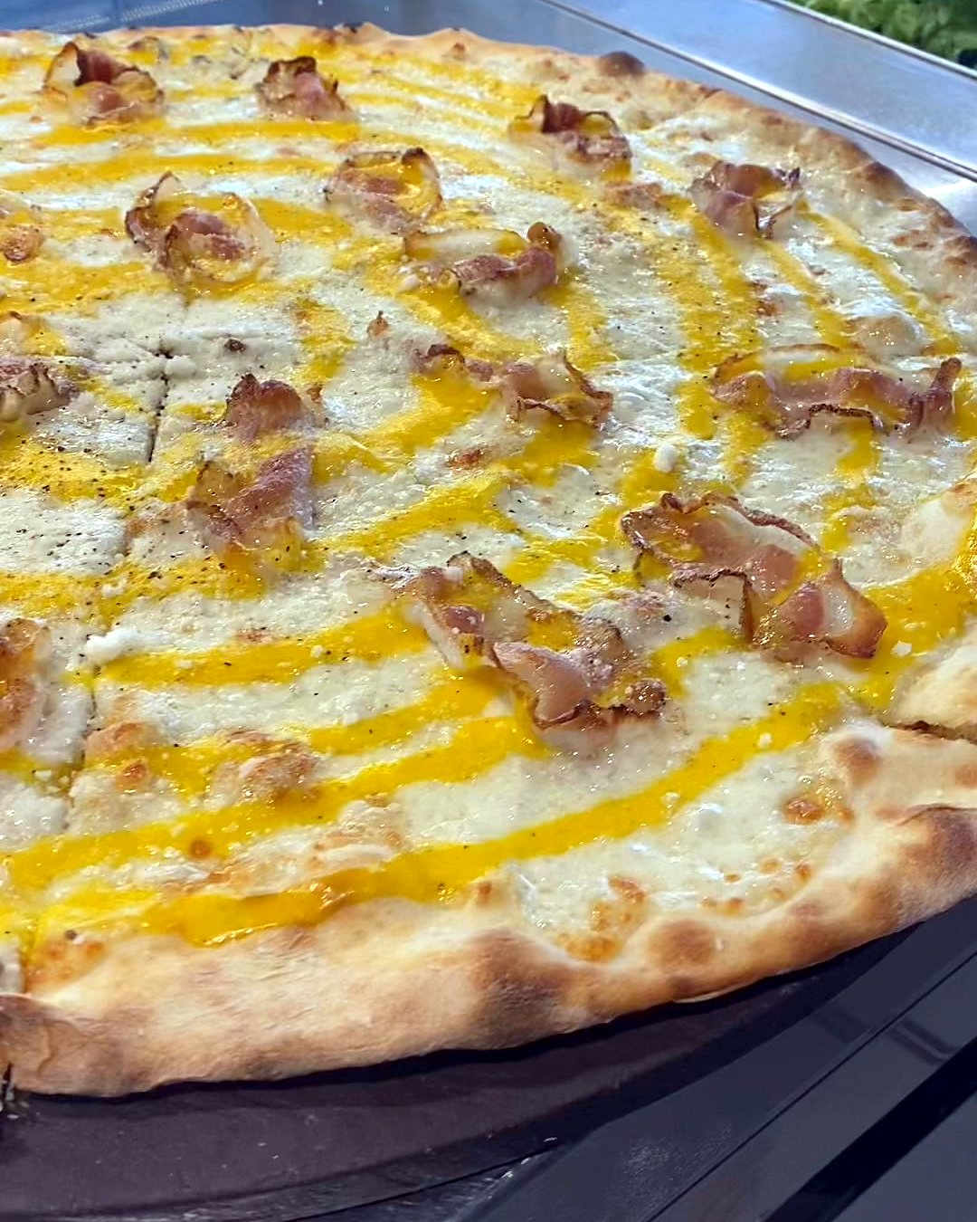 Pizza special alla Carbonara di Koko's, bianca con uovo e pancetta croccante