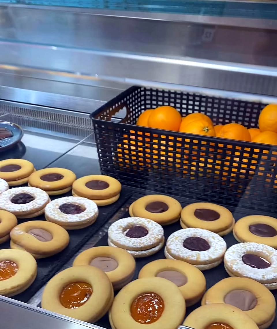 Vetrina con biscotti alla marmellata e al cioccolato e un cesto di arance
